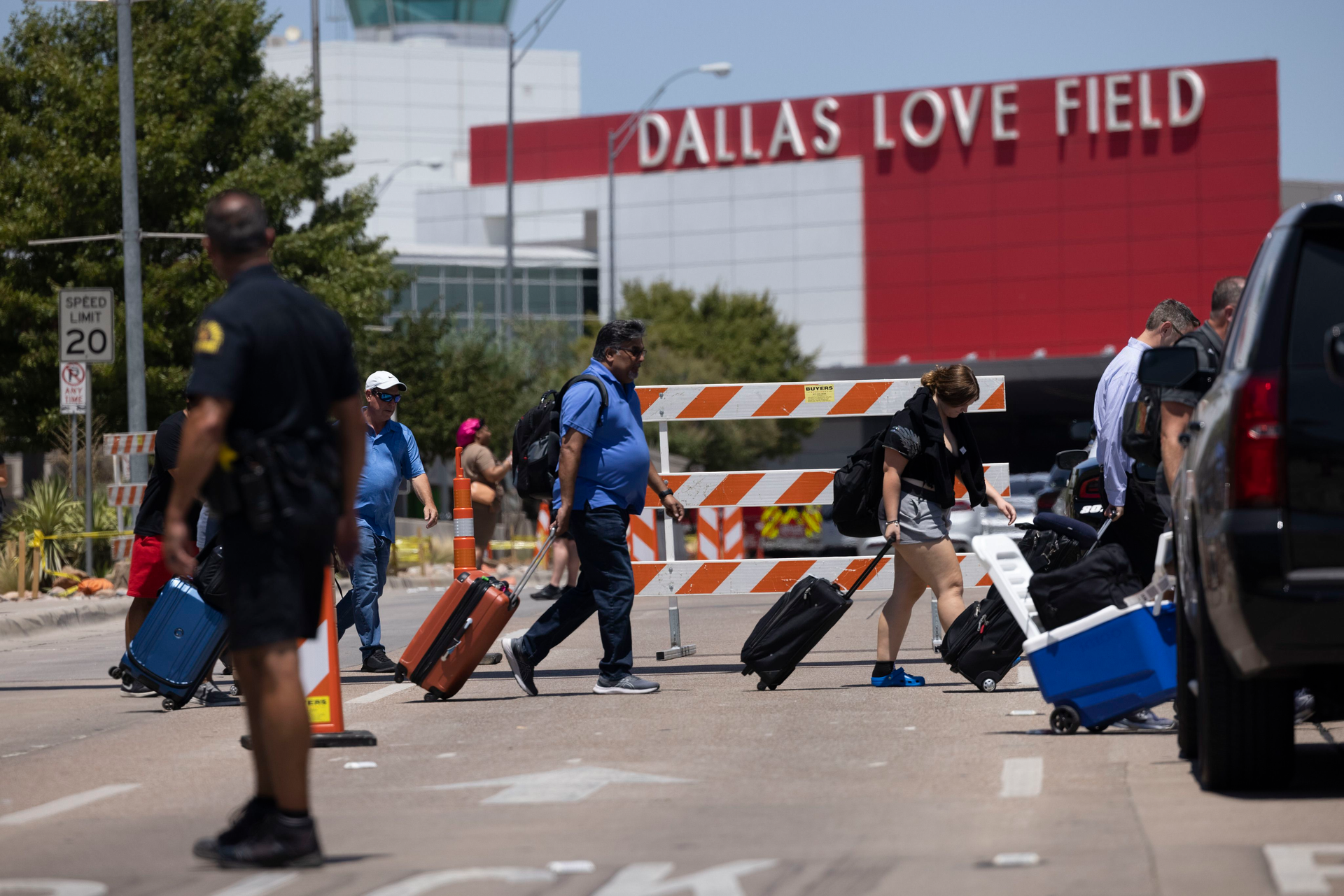 Travelers leave as Dallas police investigate reports of a shooting at Dallas Love Field airport on Monday, July 25, 2022, in Dallas, TX. A ground stop was issued at Love Field airport Monday morning after a woman fired several shots inside the terminal, Dallas police said.