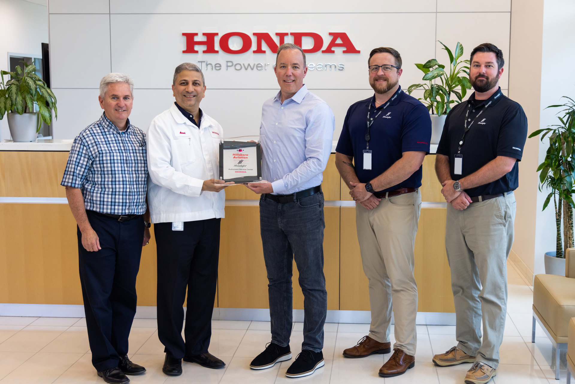 Ryan McCartney (third from the left), vice president and COO, Hillsboro Aviation, receives the Authorized Service Center plaque from Amod Kelkar (second from the left), head of the commercial business unit and vice president, customer service for Honda Aircraft Company.