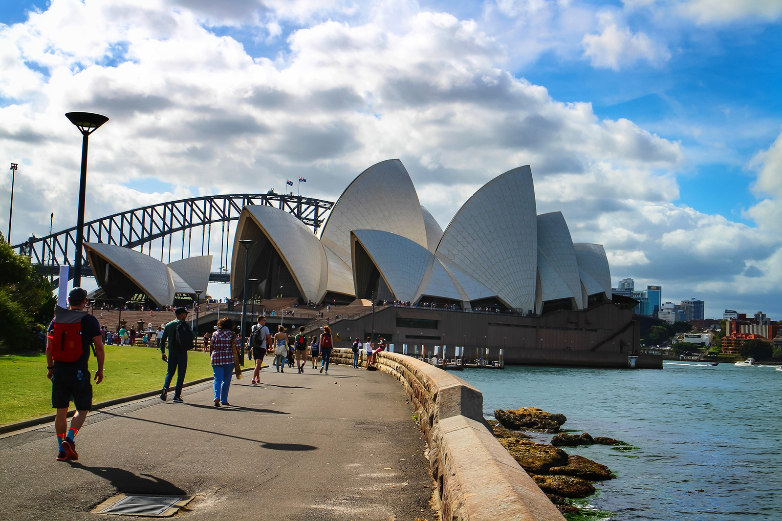 People walk along the waterfront of Sydney Harbor in Sydney, Australia, on Feb. 26, 2017. In the background is the iconic Sydney Opera House.