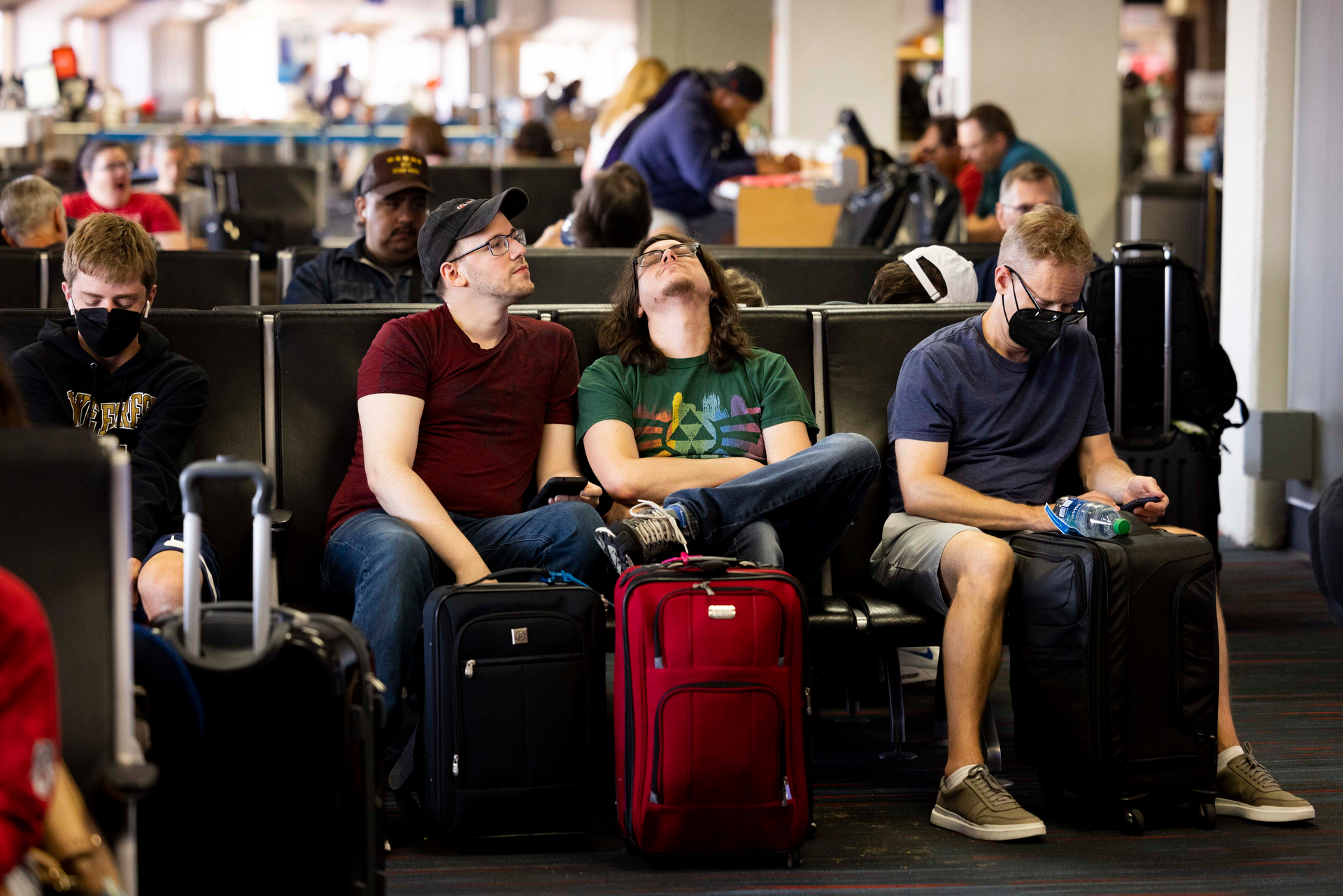 Tommy McCarver, center left, and husband Kyle Murell, center right, wait for their flight to Washington, D.C., after it was delayed about an hour at Dallas/Fort Worth International Airport on Friday, July 1, 2022.