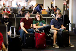 Tommy McCarver, center left, and husband Kyle Murell, center right, wait for their flight to Washington, D.C., after it was delayed about an hour at Dallas/Fort Worth International Airport on Friday, July 1, 2022.