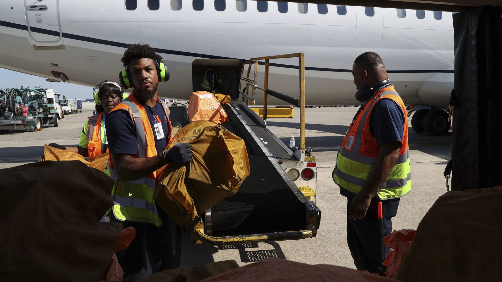 Trainees Nadia Fort, from left, Devin Lovell and Philip Brown unload a plane at O Hare International Airport on Aug. 23, 2022.