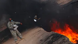 An Air Force service member tosses items into a burn pit at Balad Air Base, Iraq, in March 2008. An Air Force service member tosses items into a burn pit at Balad Air Base, Iraq, in March 2008.