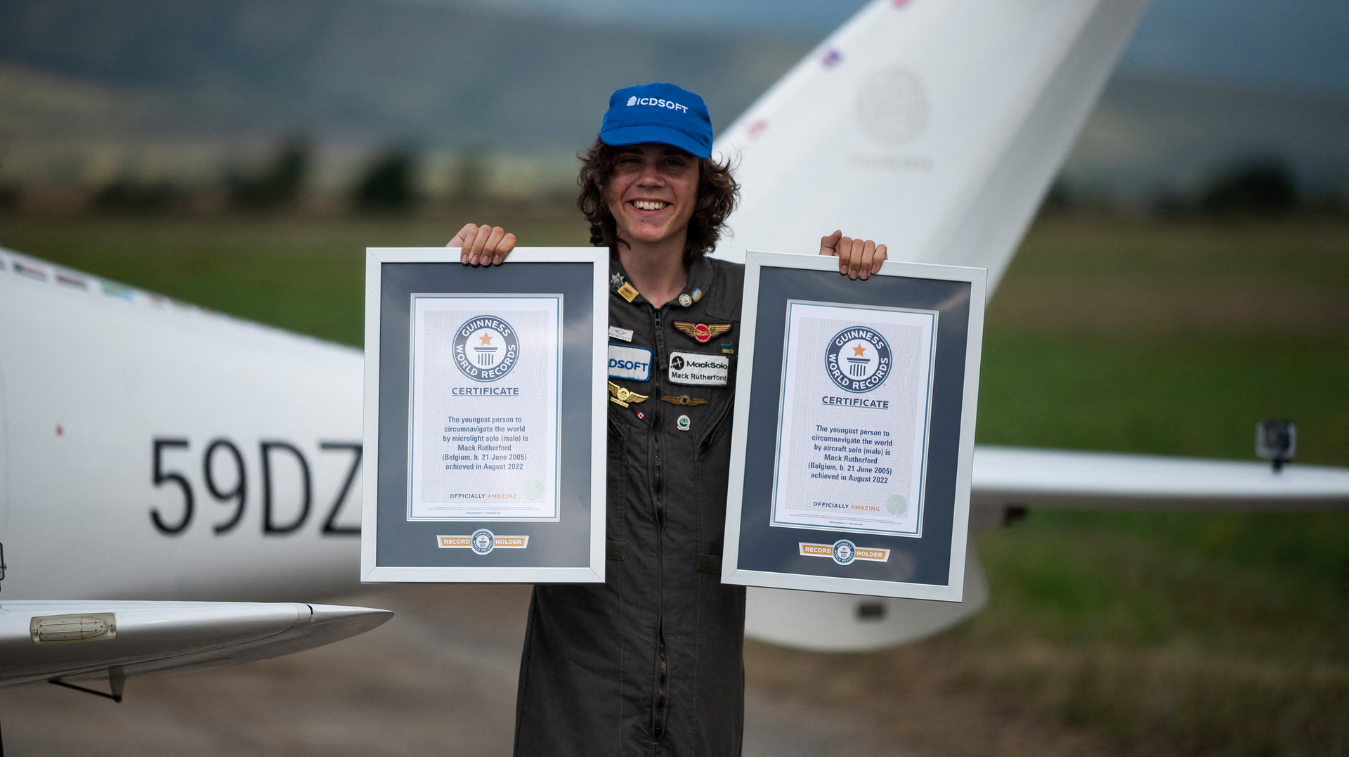 Mack Rutherford, 17, the youngest person to fly solo around the world, poses for photographers while displaying the Guiness World Record certificates, after landing at Sofia West airport near Radomir on Wednesday, Aug. 24, 2022.