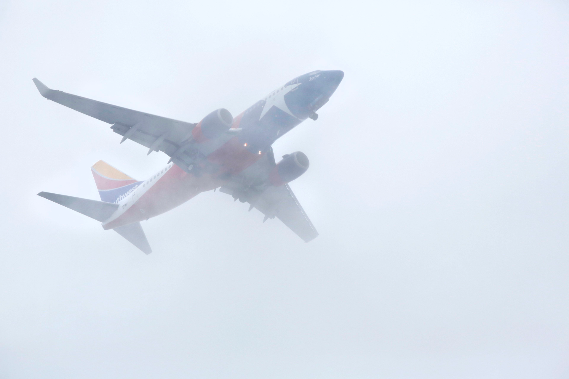 A Texas flag themed Southwest Airlines jet cuts through the low cloud bank in downtown Dallas as it makes it's approach to Love Field, Tuesday afternoon, October 16, 2018. Waves of rain are expected the rest of the week.