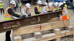 Signing the last structural station steel beam prior to it being hoisted into place.
