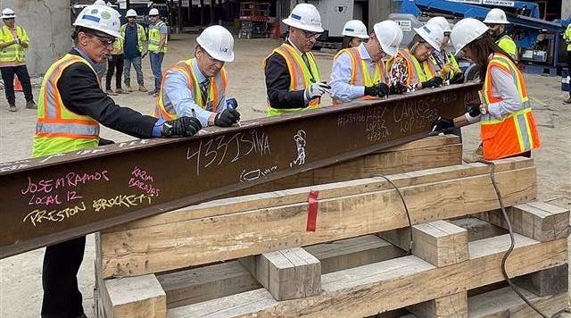 Signing the last structural station steel beam prior to it being hoisted into place.