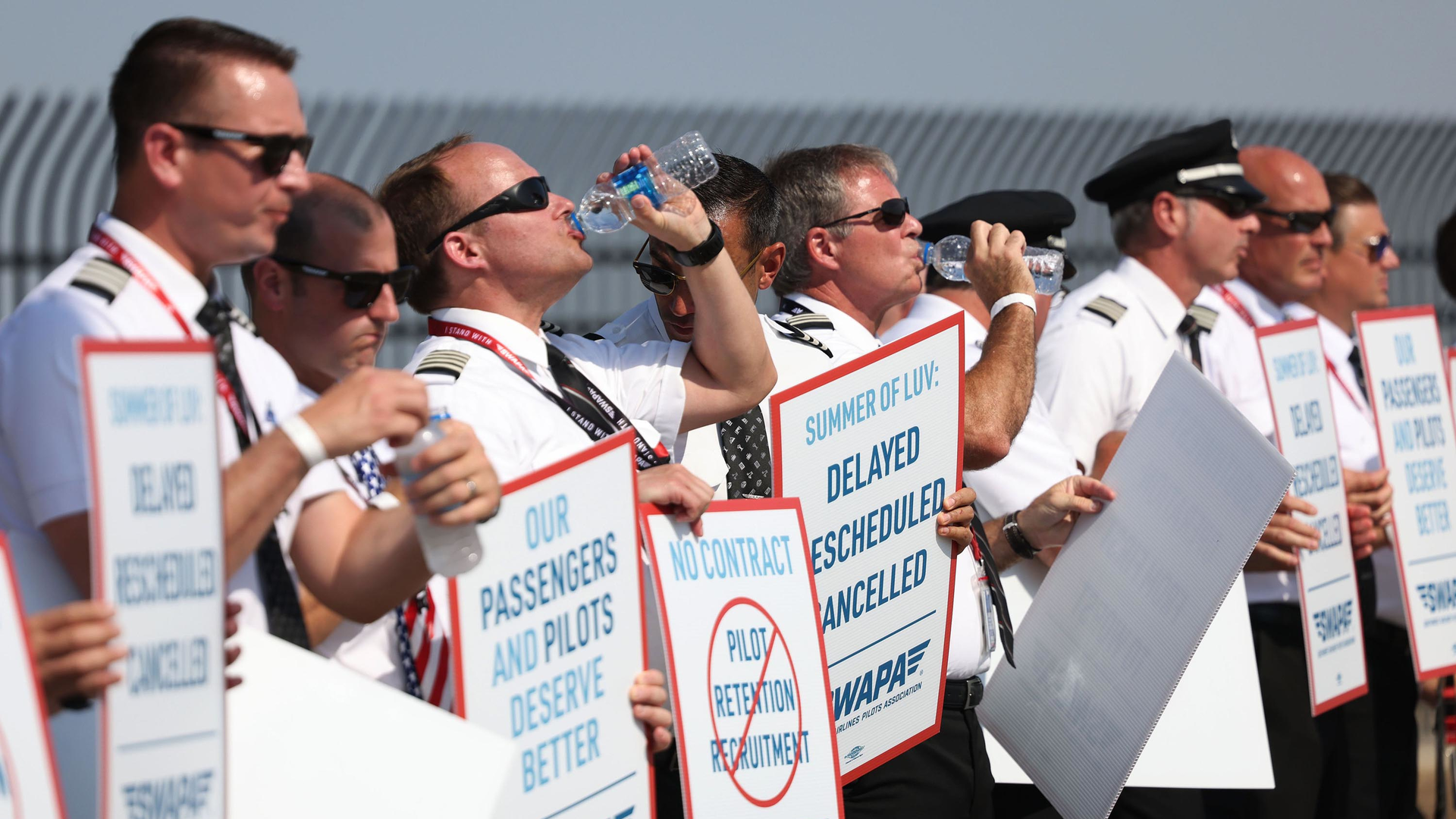 Southwest Airlines pilots drink water while picketing for better work conditions on June 21, 2022, outside Dallas Love Field.
