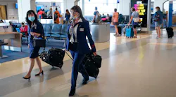 American Airlines flight attendants walk along a concourse at DFW International Airport.