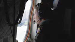 A Coast Guard flight crew member looks out the window as she's positioned to watch for any danger on a flight to Southwest Florida on Sunday, Oct. 2, 2022.
