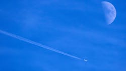 Contrails form behind a commercial jet passing by the moon over Dallas. Contrails form behind a commercial jet passing by the moon over Dallas.