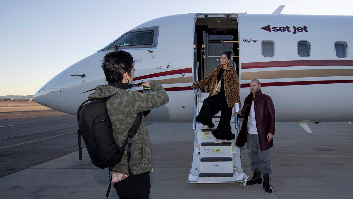Actors Vanessa Hudgens, center, and Oliver Trevena, right, pose for photographs in front of a Set Jet aircraft during a groundbreaking event at the Atlantic Aviation terminal on Tuesday, Dec. 13, 2022, in Las Vegas. Set Jet is a subscription flight service using private jets. (Ellen Schmidt/Las Vegas Review-Journal) @ellenschmidttt
