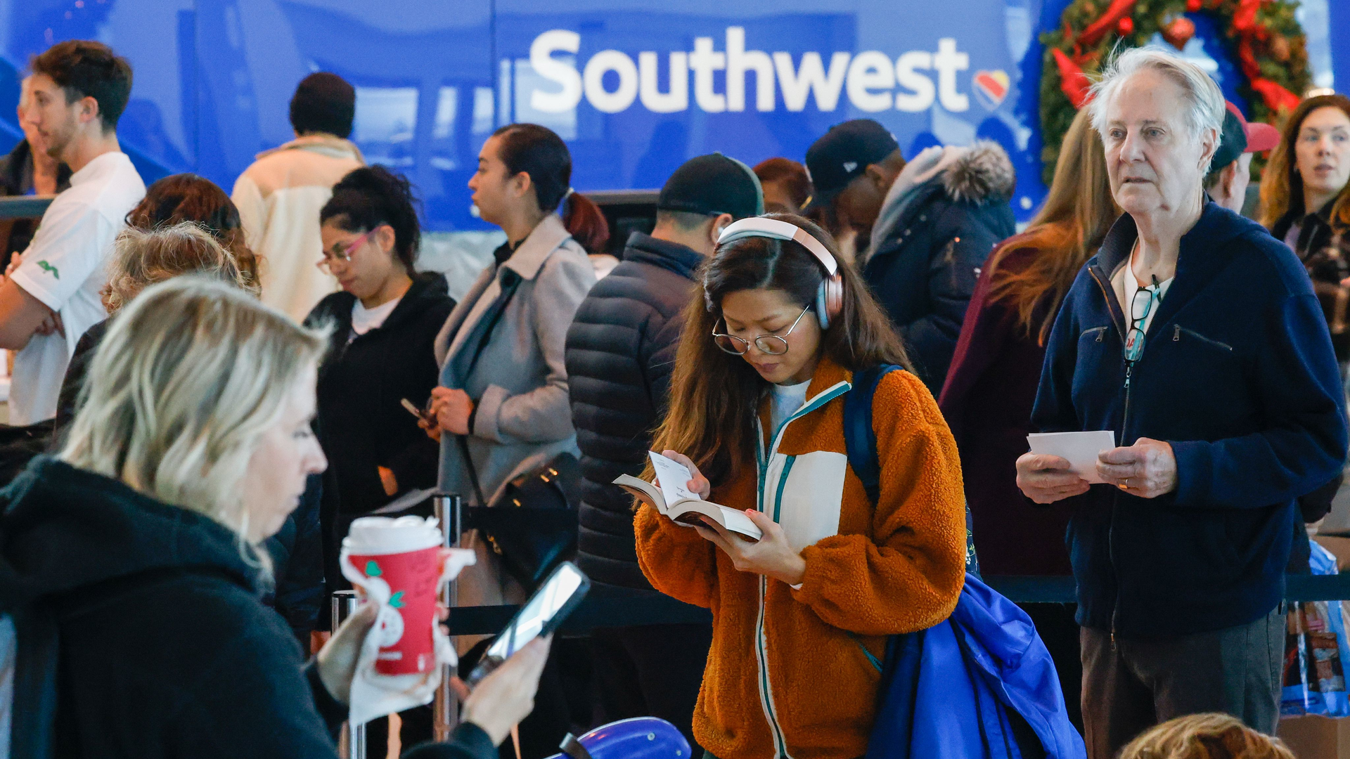Ketmany Rasasack reads as she waits in line to reach a Southwest Airlines ticket counter at Dallas Love Field Airport on Tuesday. Rasasack s original flight was canceled the day before.
