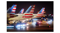 Baggage carts pass American Airlines planes at the gates of Terminal C at Dallas/Fort Worth International Airport.