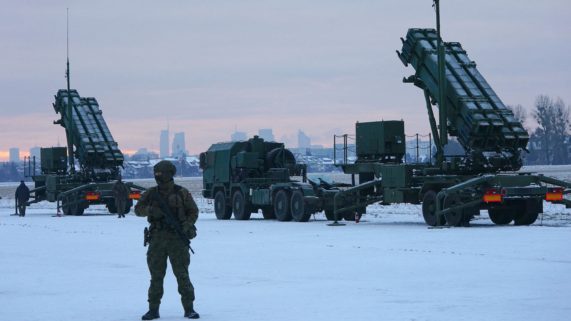 A soldier stands in front of PATRIOT (Phased Array Tracking Radar to Intercept on Target) surface-to-air missile systems during a military exercise at Warsaw Babice Airport, Poland on Feb. 7, 2023.