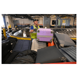 Hayden Vallier, a ramp supervisor for Southwest Airlines, pulls luggage from the baggage handling system onto a cart to be loaded onto a plane at the new KCI single terminal which is operating with a state-of-the-art $54 million baggage handling system.