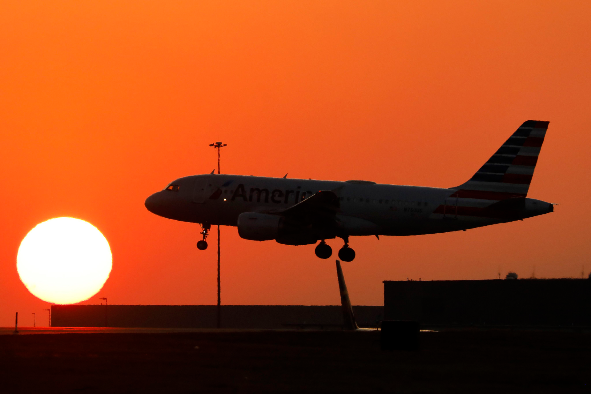 An American Airlines jet lands before the setting sun at Dallas/Fort Worth International Airport, Feb. 15, 2023.
