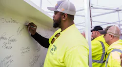 Eugene Walker, Heavy Equipment Operator for the Allegheny County Airport Authority, signs the final steel beam for the airport’s new terminal structure.