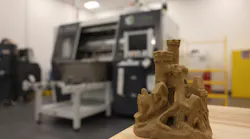 A model sandcastle sits on a table in front of an ExOne S-Print sand 3D printer at Tinker Air Force Base, Okla., April 13, 2023. The 76th Commodity Maintenance Group’s new foundry can sand cast aluminum parts up to 120 pounds, providing another avenue for sourcing aircraft parts not easily obtained through traditional contracting methods.