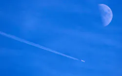 Contrails form behind a commercial jet passing by the moon over Dallas, November 30, 2022. Contrails form behind a commercial jet passing by the moon over Dallas, November 30, 2022.