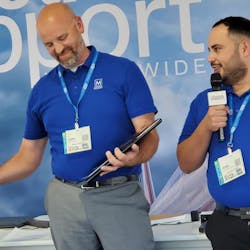 Ground Support Worldwide editor Josh Smith (at left) shakes hands with John Vollbrecht of Menzies TPA while Jose Valenzuela of Menzies TPA is at the mic. Menzies TPA is the winner of the first Ground Support Team of the Year award.