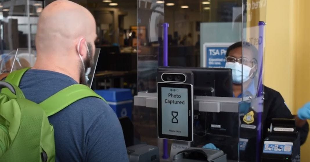A traveler removes his mask to enable the tablet to capture his photo to immediately verify that his face matches the face on his ID.