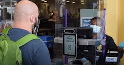 A traveler removes his mask to enable the tablet to capture his photo to immediately verify that his face matches the face on his ID. A traveler removes his mask to enable the tablet to capture his photo to immediately verify that his face matches the face on his ID.