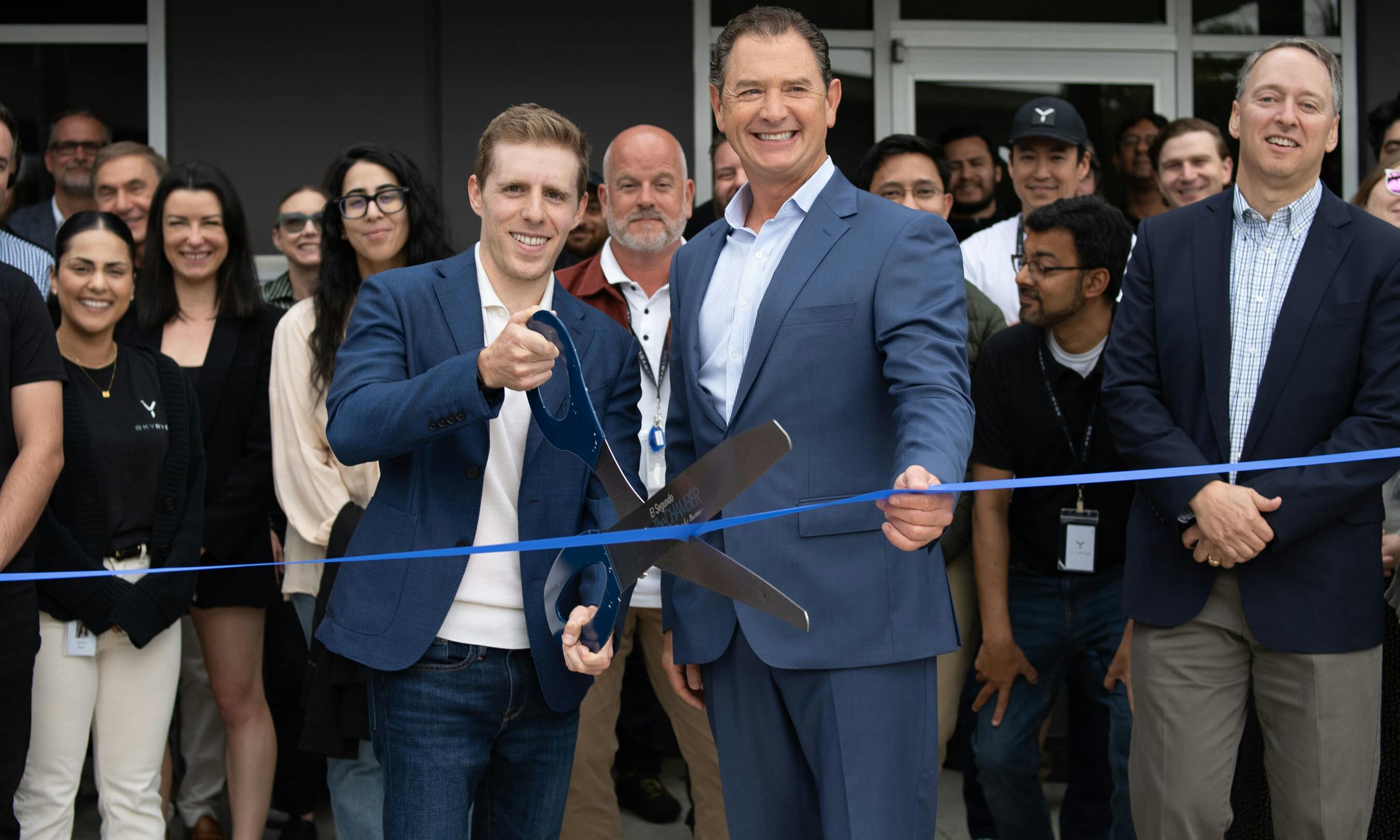 Skyryse CEO Mark Groden and El Segundo, CA Mayor Drew Boyles cut the ribbon the latest additional Skyryse facility, with Skyryse employees looking on behind them.