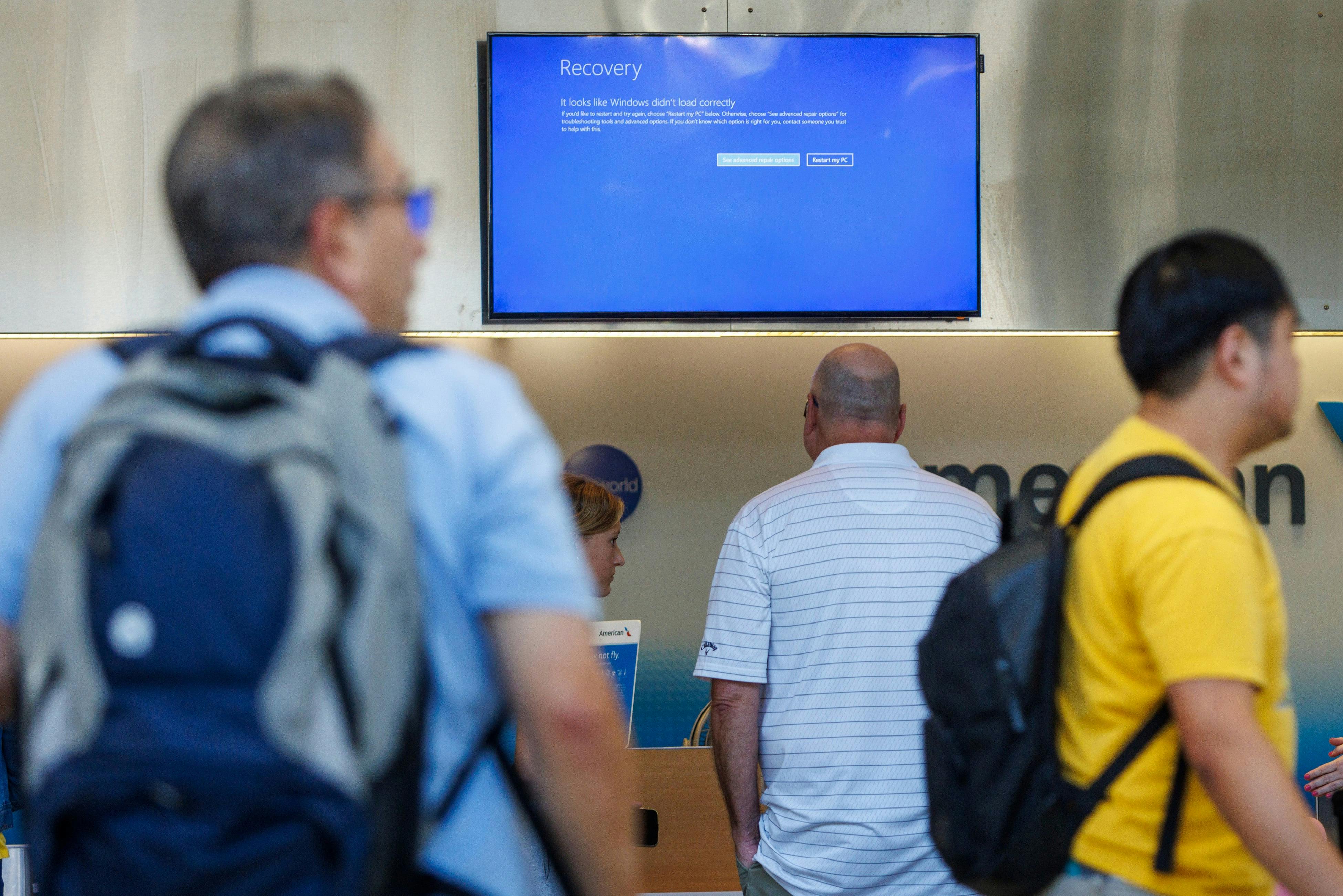 A sign over check-in agents reads 'Recovery, It looks like Windows didn't load correctly' at Philadelphia International Airport during a system outage delaying travel on Friday, July 19, 2024.