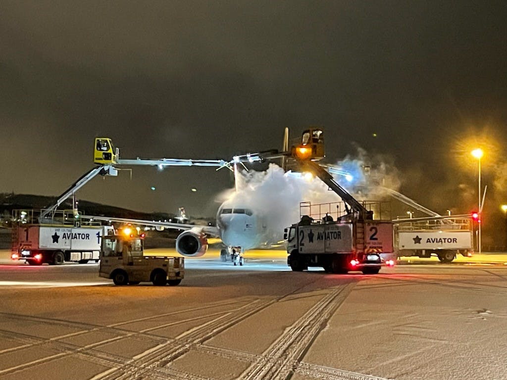 Removing ice from aircraft involves careful movement of machinery and personnel with caution during hostile outdoor conditions.
