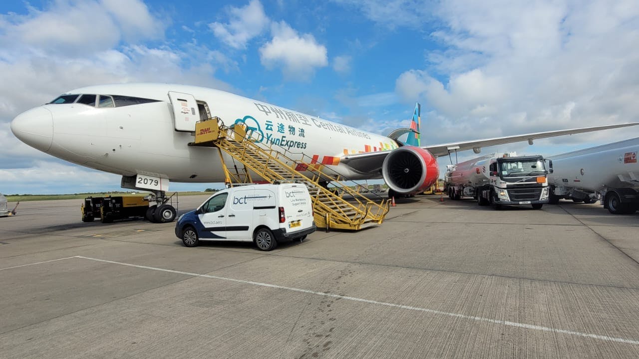 An airplane with the logo for YunExpress sits on the tarmac with a yellow mobile staircase attached and a cargo van in front