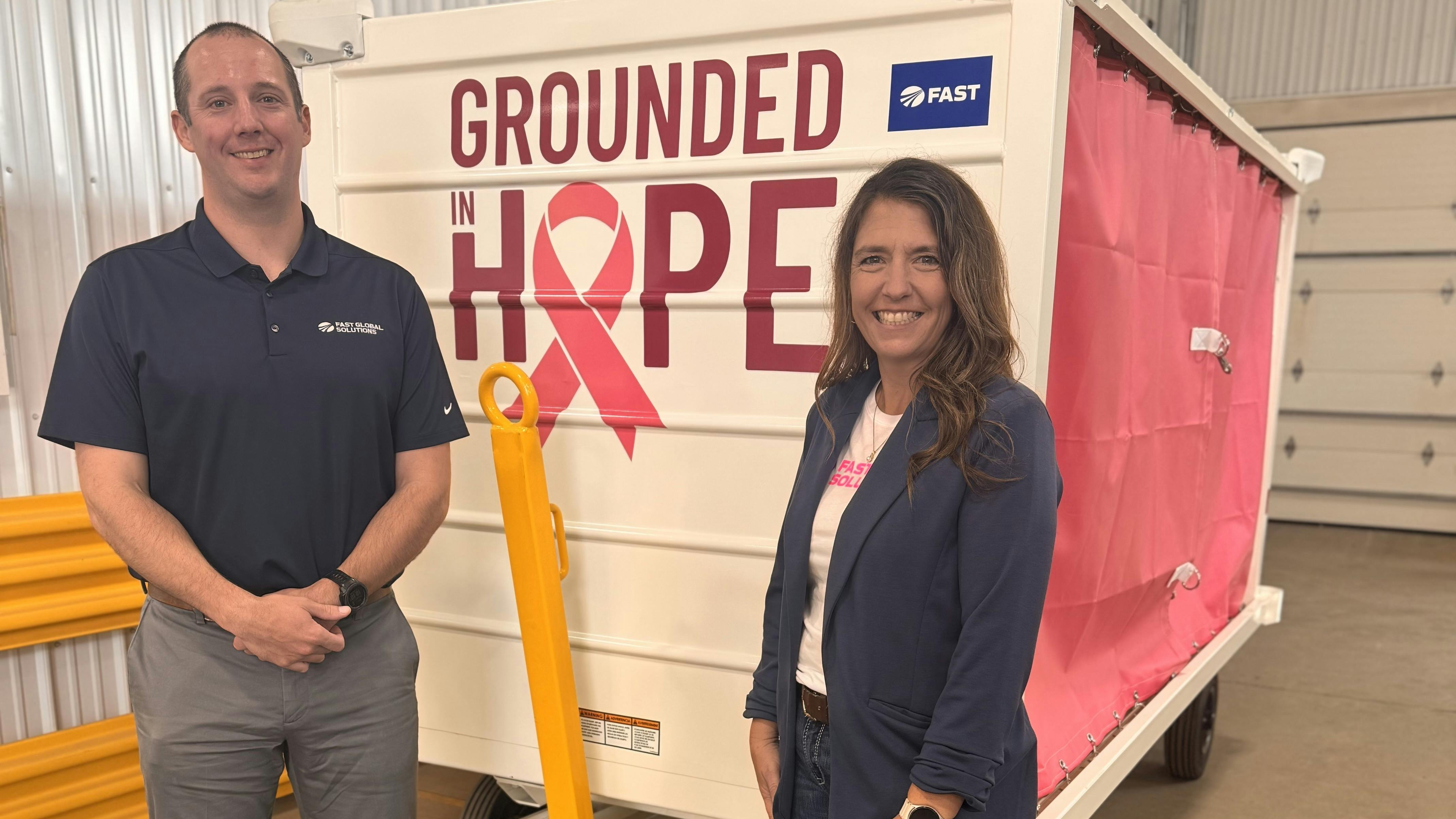 Joey Sisser and Angie Betterman from the FAST Global Solutions GSE Sales Team pose with the Grounded for Hope baggage cart that will be autioned off at the International GSE Expo in Las Vegas this week.