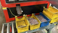 A group of yellow and blue plastic bins filled with coated metal threaded inserts on a conveyor belt A group of yellow and blue plastic bins filled with coated metal threaded inserts on a conveyor belt