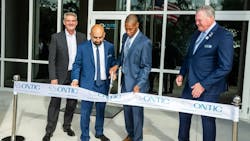 Four men wearing suits stand at a ribbon cutting ceremony with one cutting a ribbon with metal scissors Four men wearing suits stand at a ribbon cutting ceremony with one cutting a ribbon with metal scissors