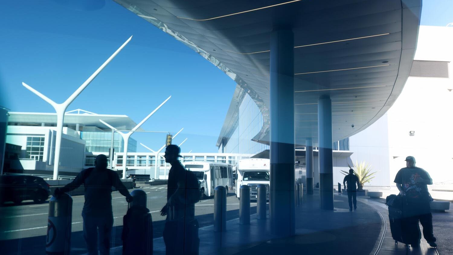 LOS ANGELES, CA - OCTOBER 29, 2025 -- Travelers are reflected in a Terminal 4 window at Los Angeles International Airport on October 29, 2025. This is the second day that air traffic controllers will not receive a paycheck due to the U.S. government shut down, even as controllers work mandatory overtime six days a week and 10 hours a day. (Genaro Molina/Los Angeles Times)
