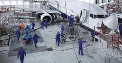 A group of maintenance technicians in blue clothing work on an airplane in an aircraft hangar A group of maintenance technicians in blue clothing work on an airplane in an aircraft hangar