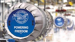 A close-up shot of an airplane engine with a blue graphic in front that reads, 'Pratt & Whitney Dependable Engines Powering Freedom' A close-up shot of an airplane engine with a blue graphic in front that reads, 'Pratt & Whitney Dependable Engines Powering Freedom'