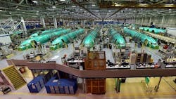 An aircraft hangar shows a row of green airplanes behind an assembly line An aircraft hangar shows a row of green airplanes behind an assembly line
