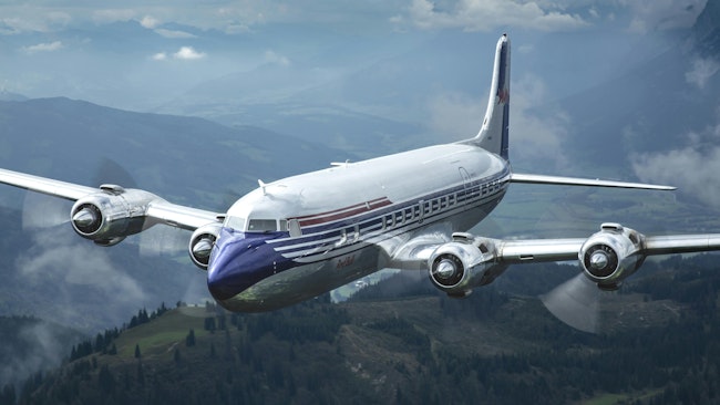 A DC-6 aircraft with a blue nose and red stripes flies over dark mountains and trees