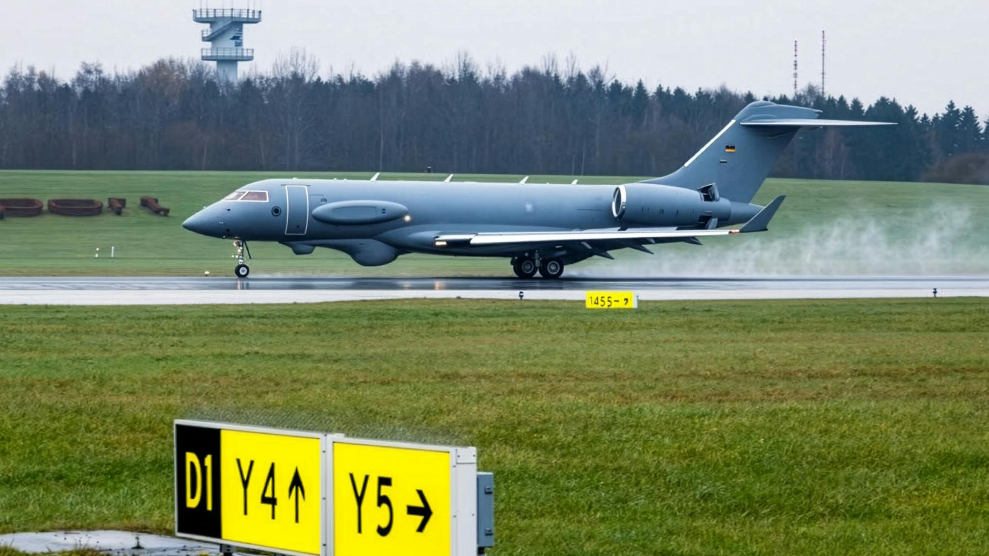 An airplane lands on a runway with steam behind it and a yellow sign in front of it