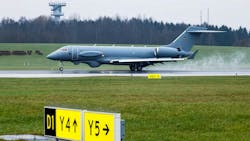 An airplane lands on a runway with steam behind it and a yellow sign in front of it An airplane lands on a runway with steam behind it and a yellow sign in front of it
