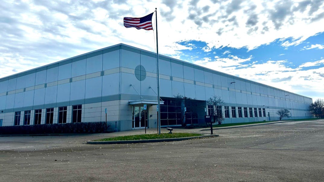 A large building with glass windows in geometric designs with a United States flag in front of it