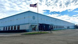 A large building with glass windows in geometric designs with a United States flag in front of it A large building with glass windows in geometric designs with a United States flag in front of it