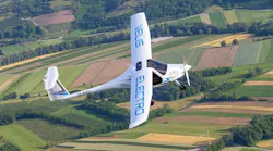 A white airplane featuring blue text that reads, 'VELIS ELECTRO' flies over rows of brown and green fields