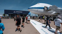 A wide shot of Boeing Plaza at EAA AirVenture, showcasing an airplane, a crowd of people and a building with the word 'BOEING' on it