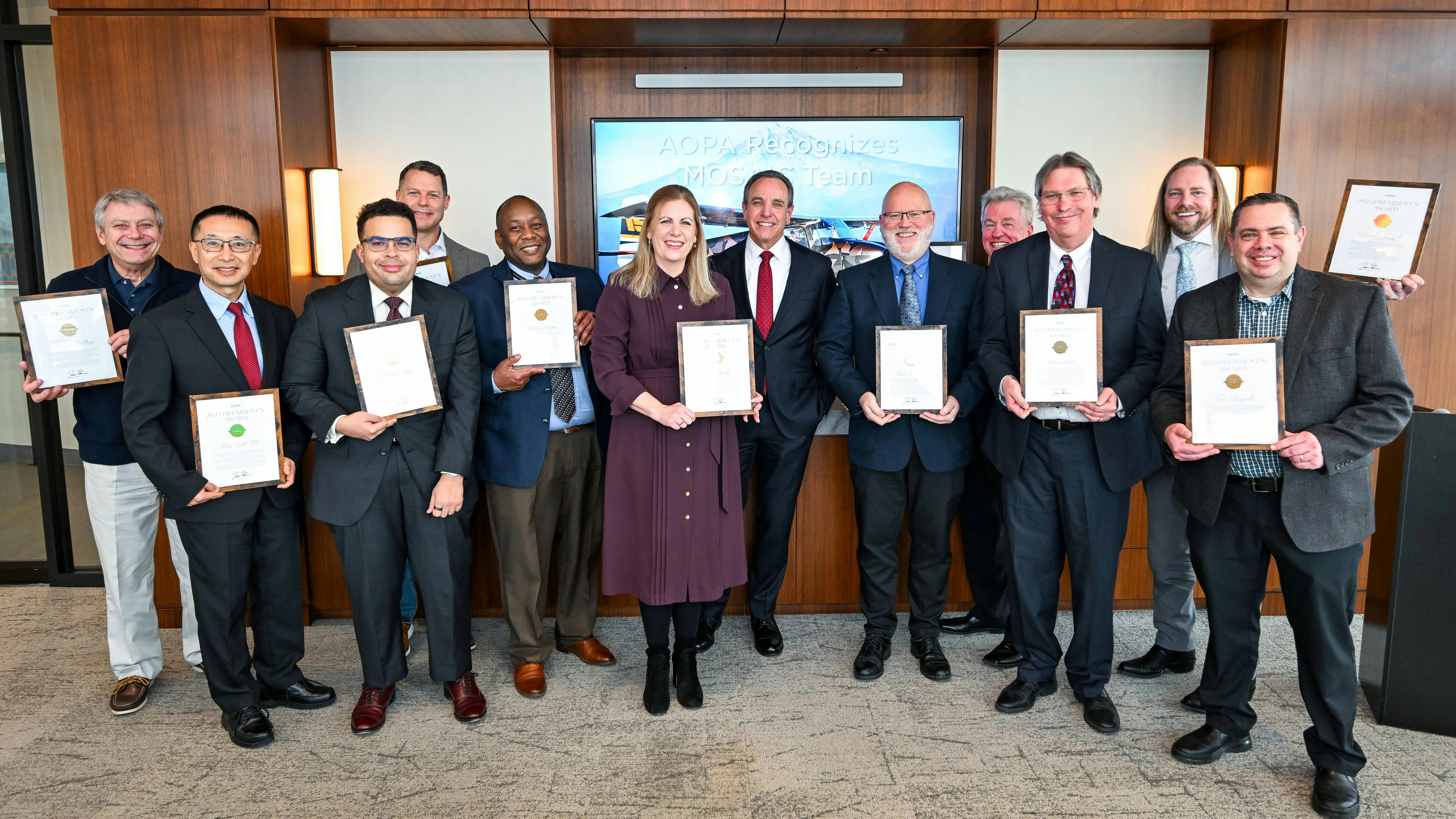 A group of people in professional attire and holding certificates smiles at the camera