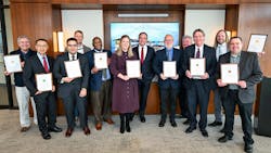 A group of people in professional attire and holding certificates smiles at the camera A group of people in professional attire and holding certificates smiles at the camera