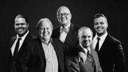 A black-and-white photograph of a group of men wearing suits and smiling at the camera A black-and-white photograph of a group of men wearing suits and smiling at the camera