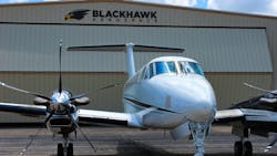 An airplane with a 5-blade propeller sits parked in front of an aircraft hangar with a sign on the front that reads: BLACKHAWK Aerospace An airplane with a 5-blade propeller sits parked in front of an aircraft hangar with a sign on the front that reads: BLACKHAWK Aerospace