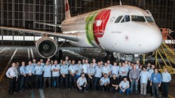 A large group of aviation maintenance technicians wearing blue shirts standing in front of an airplane A large group of aviation maintenance technicians wearing blue shirts standing in front of an airplane